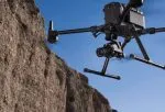 Dron con cámara volando junto a un acantilado