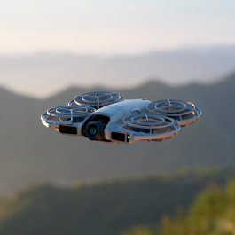 Drone volando en montaña al atardecer.